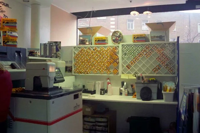 An old photo processing counter filled with Kodak film boxes from the early 2000s
