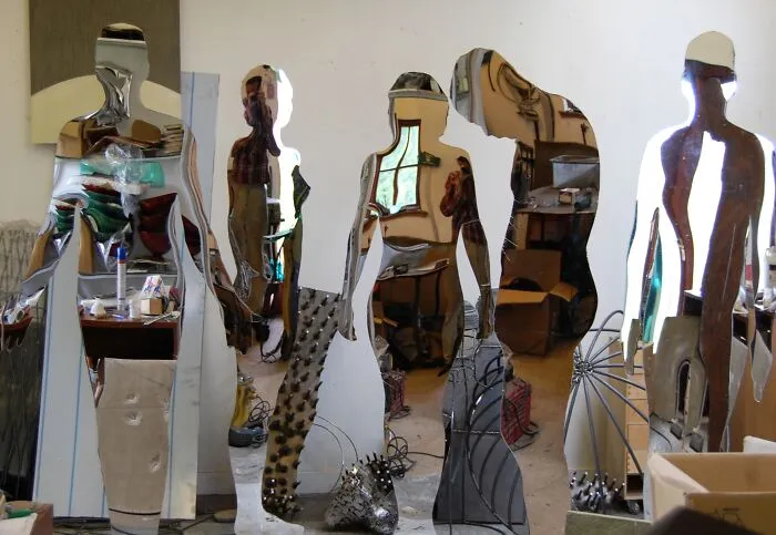 Reflective sculptures indoors showing distorted reflections of workshop and objects