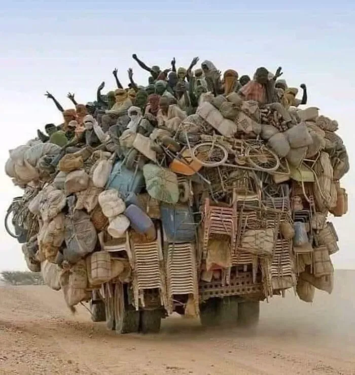 Overloaded truck carrying many people and belongings in a moving fails scene