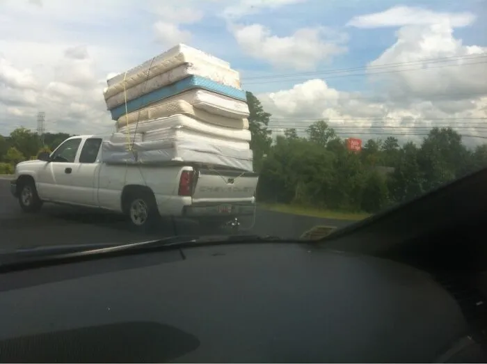 Pickup truck dangerously loaded with multiple mattresses stacked high in moving fails pics