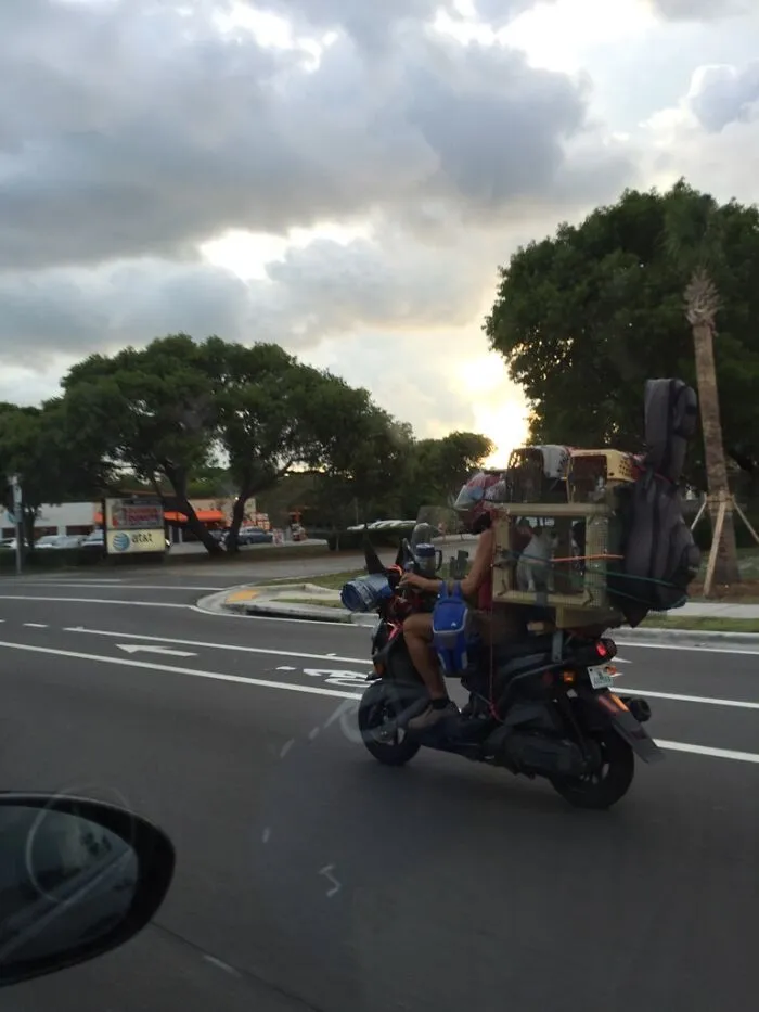 Motorcycle carrying large items stacked high in unusual moving fails situation