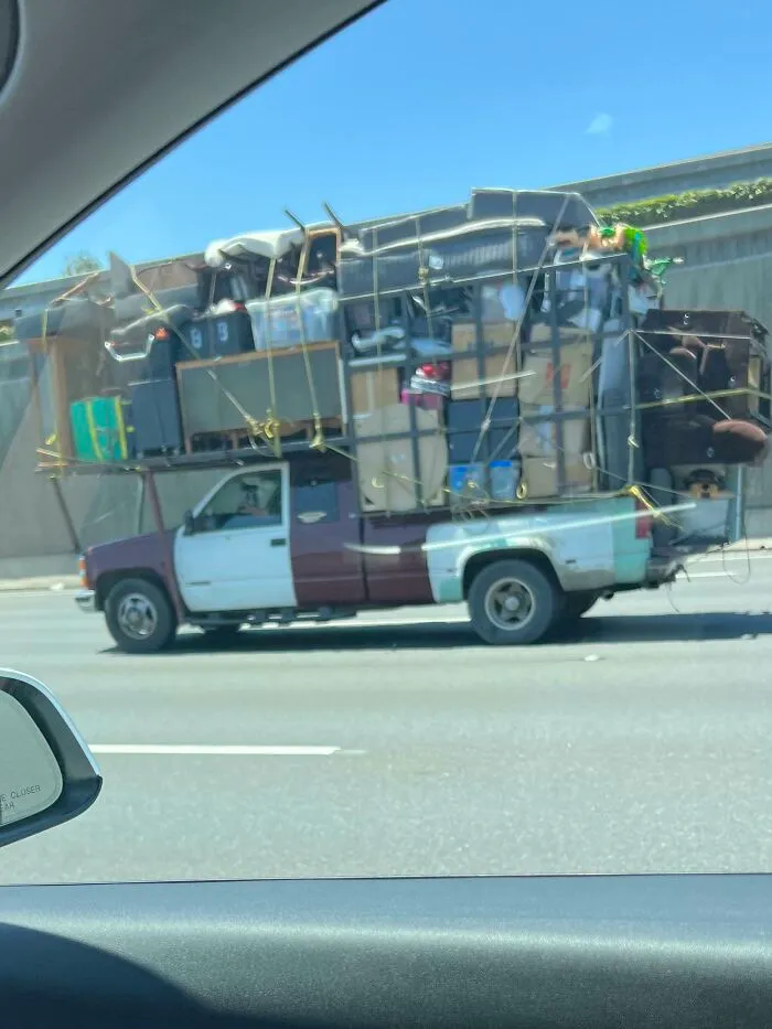Pickup truck overloaded with household items secured by ropes, a moving fails example.