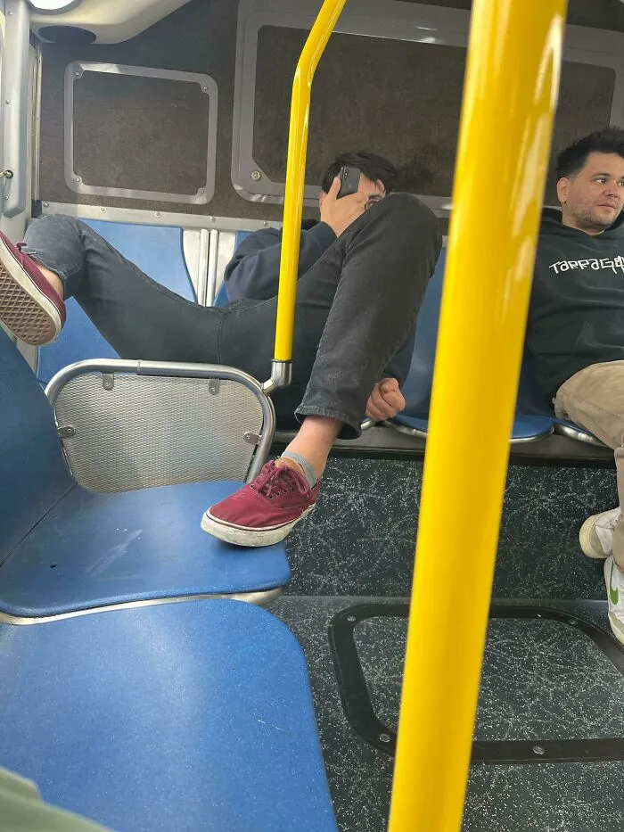 A passenger resting his dirty shoes on a bus seat, representing annoying public transport interactions.