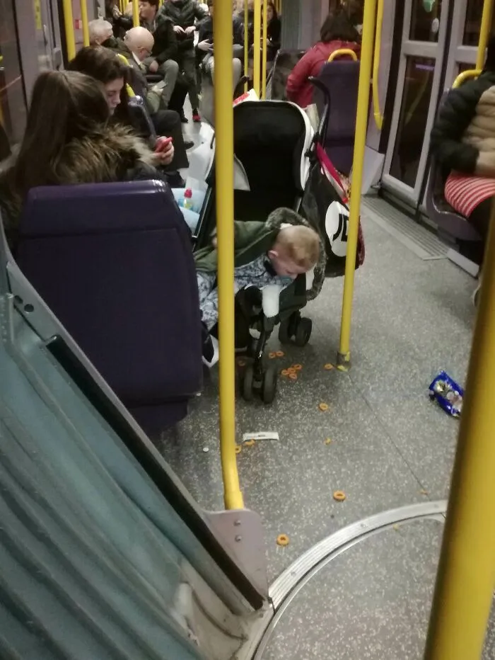 Child in stroller with dropped cereal on floor showing wild public transport interactions on a bus
