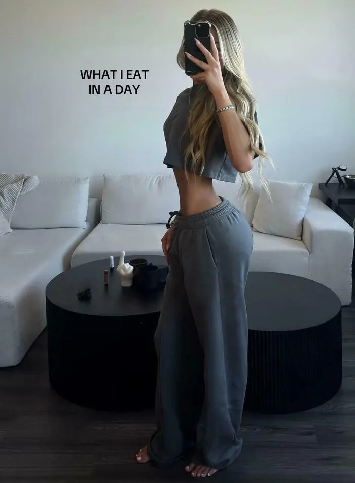 Woman posing in a mirror selfie with an extremely photoshopped waist showcasing Instagram Reality