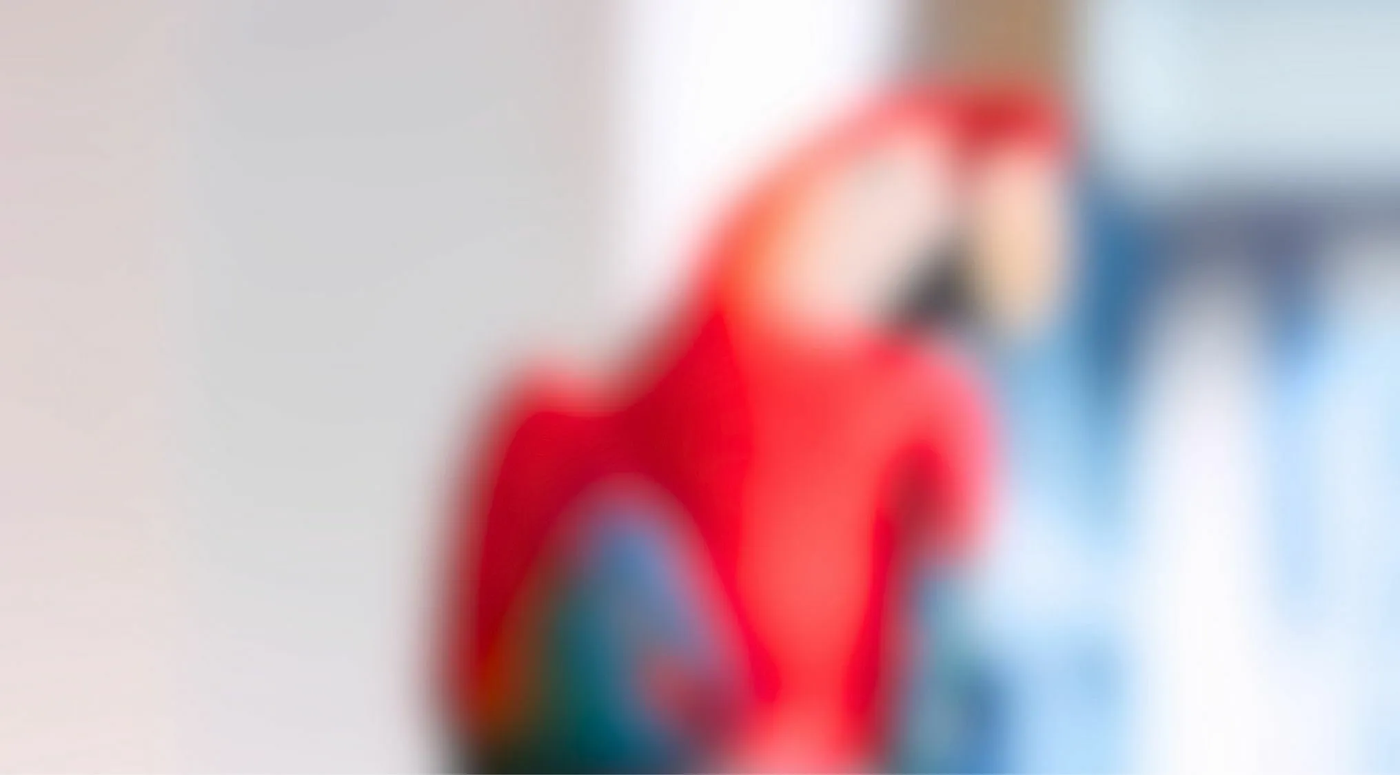 Blurry image of a red bird with green and blue feathers