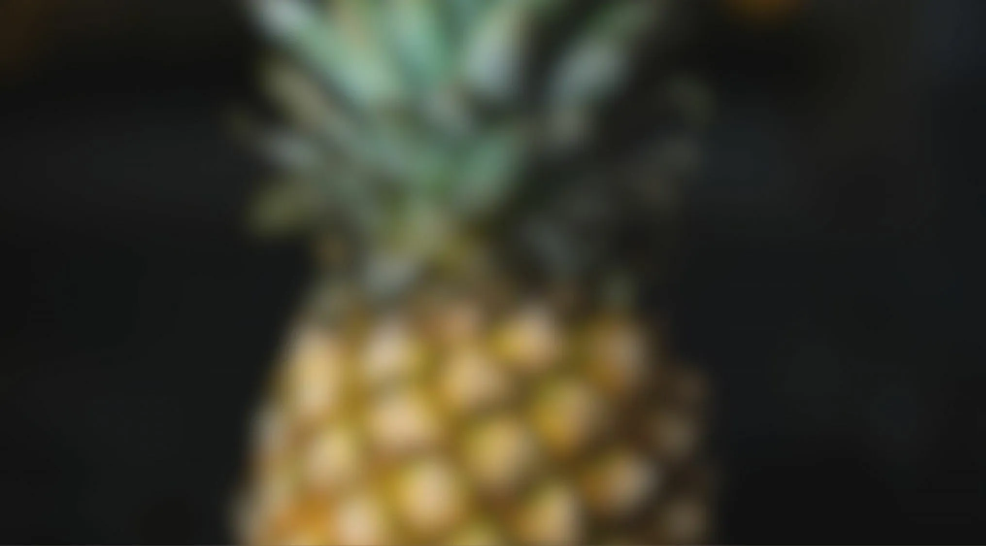 Blurry close up of pineapple with green leaves