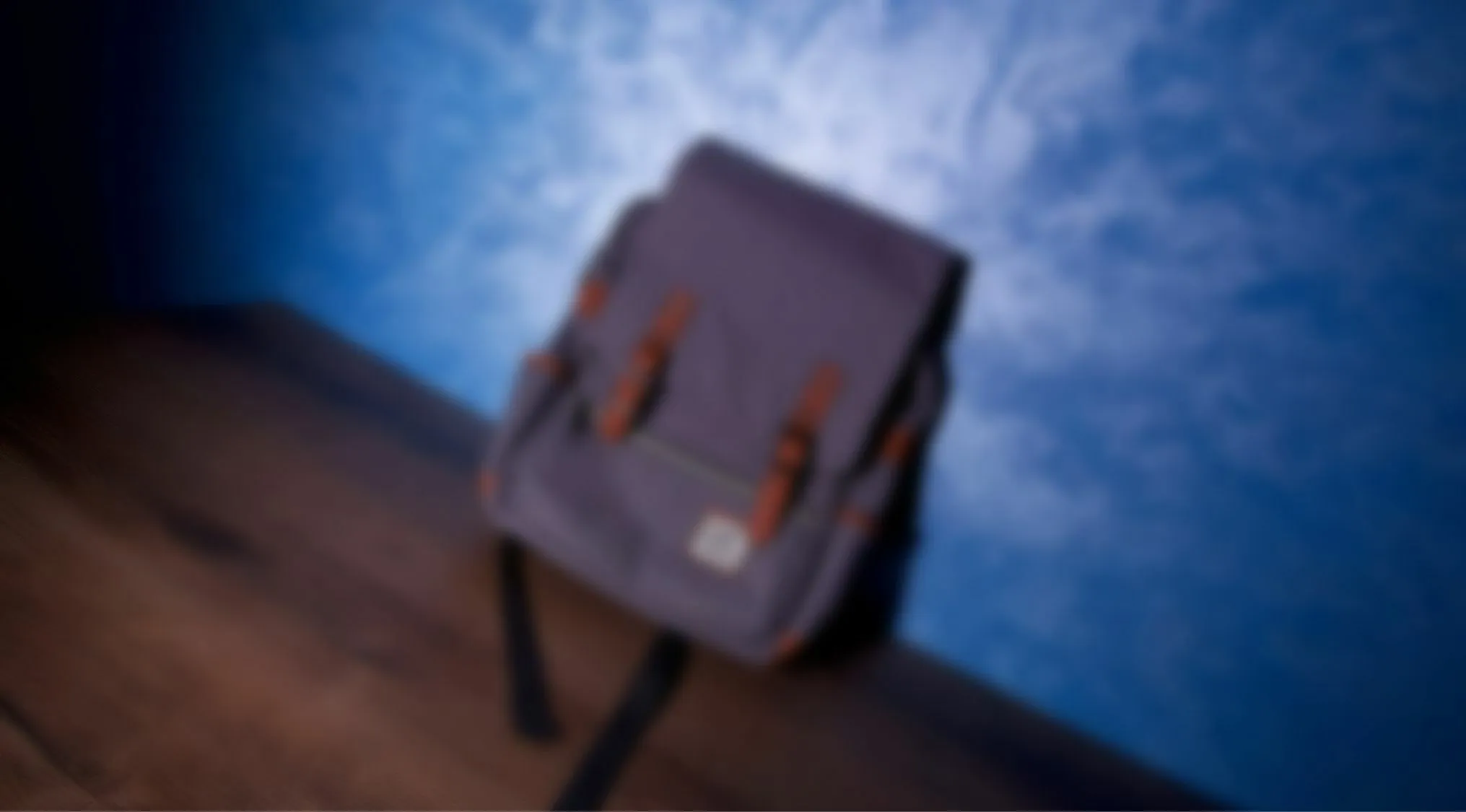 Blurry images eyesight trivia quiz with an unclear backpack on wooden surface and blue wall