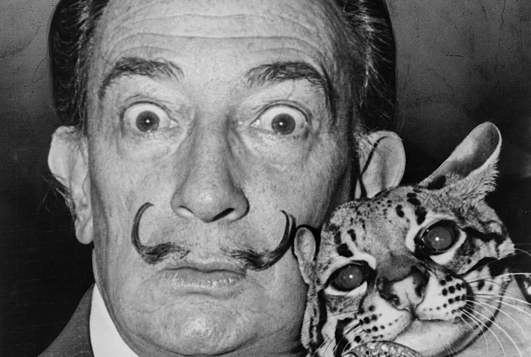 Black and white photograph of Salvador Dali with wide eyes and his signature mustache holding an ocelot