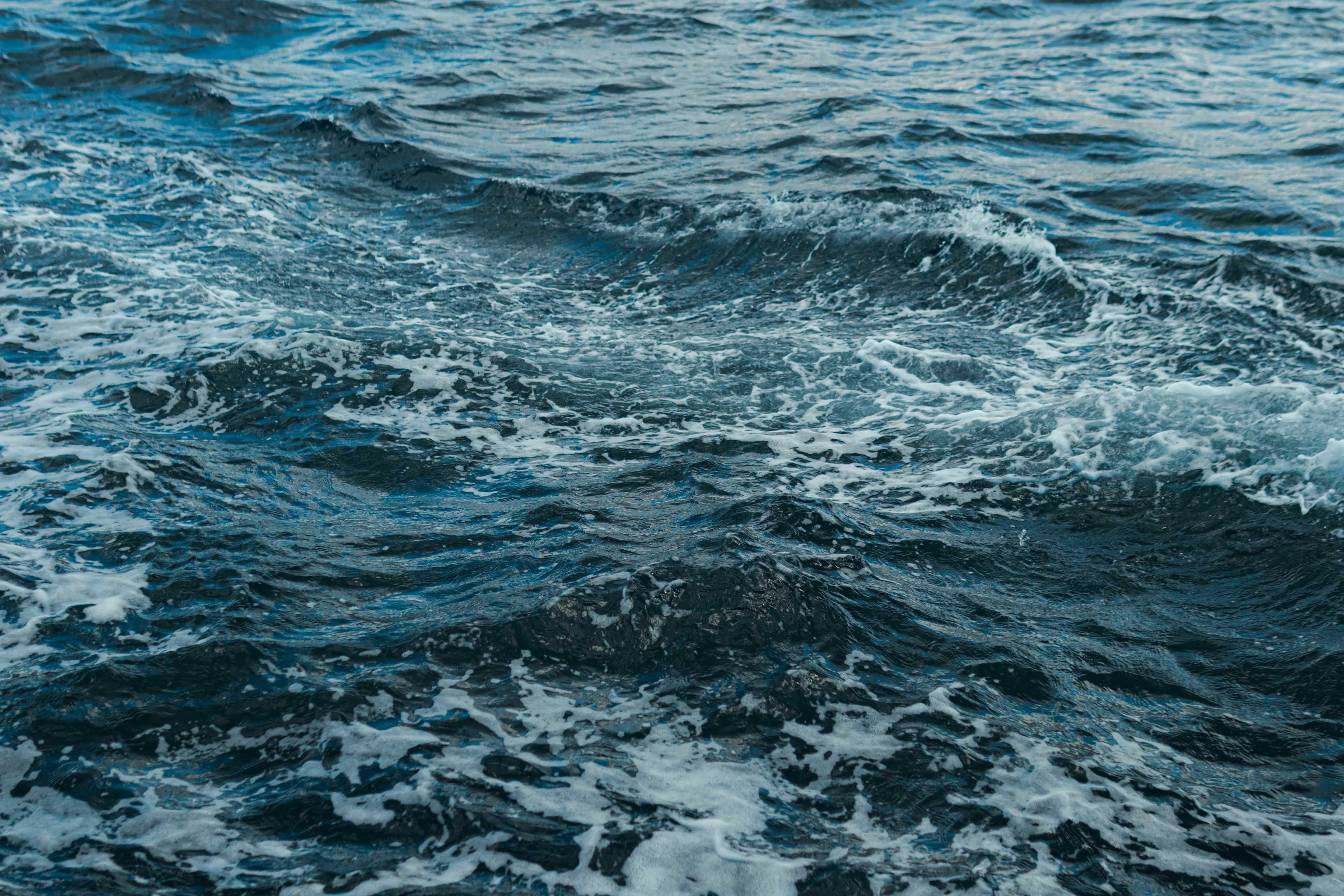 Choppy blue sea water under a cloudy sky representing which ocean is the smallest.