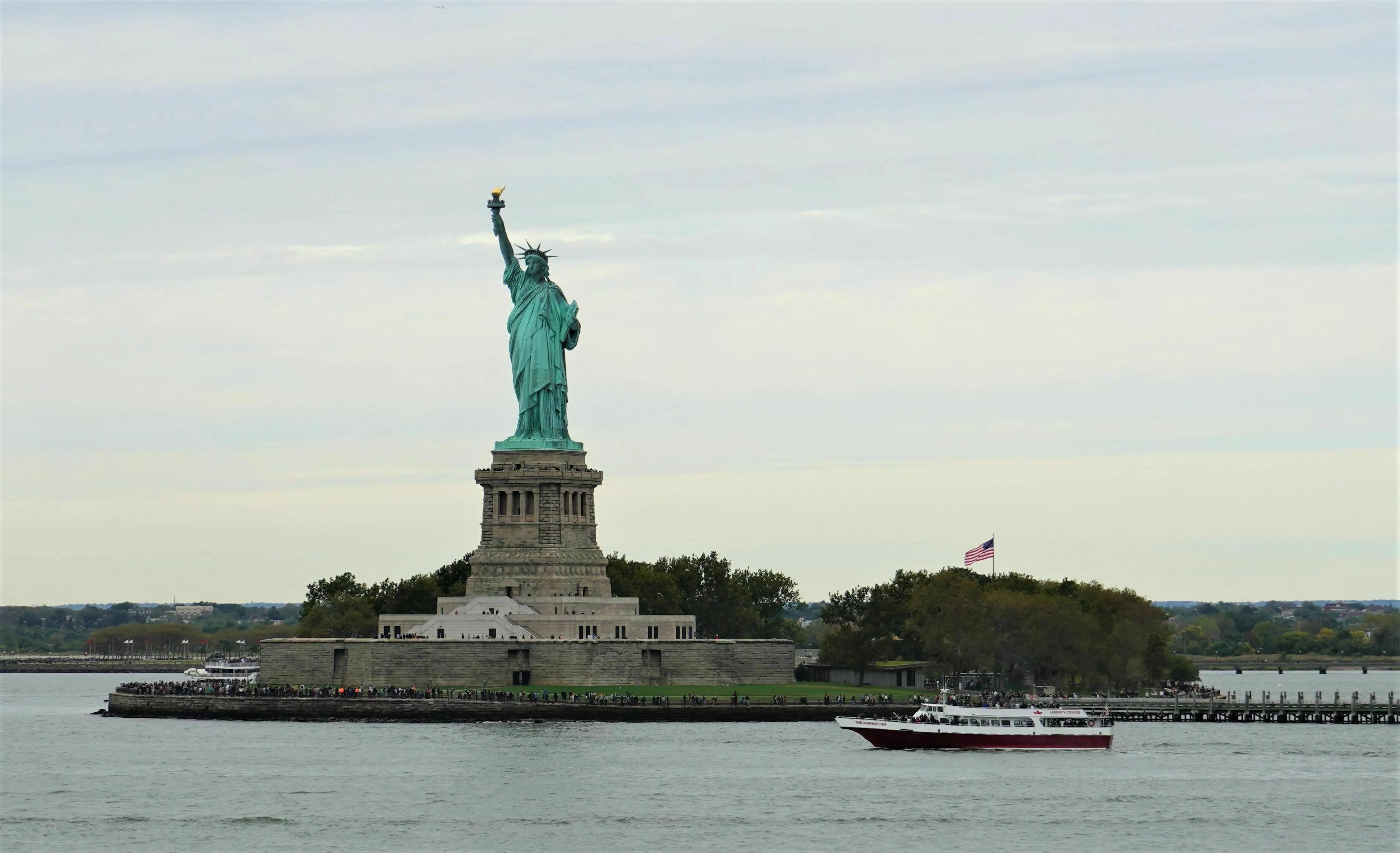 The Statue of Liberty standing tall on its island pedestal in the harbor.