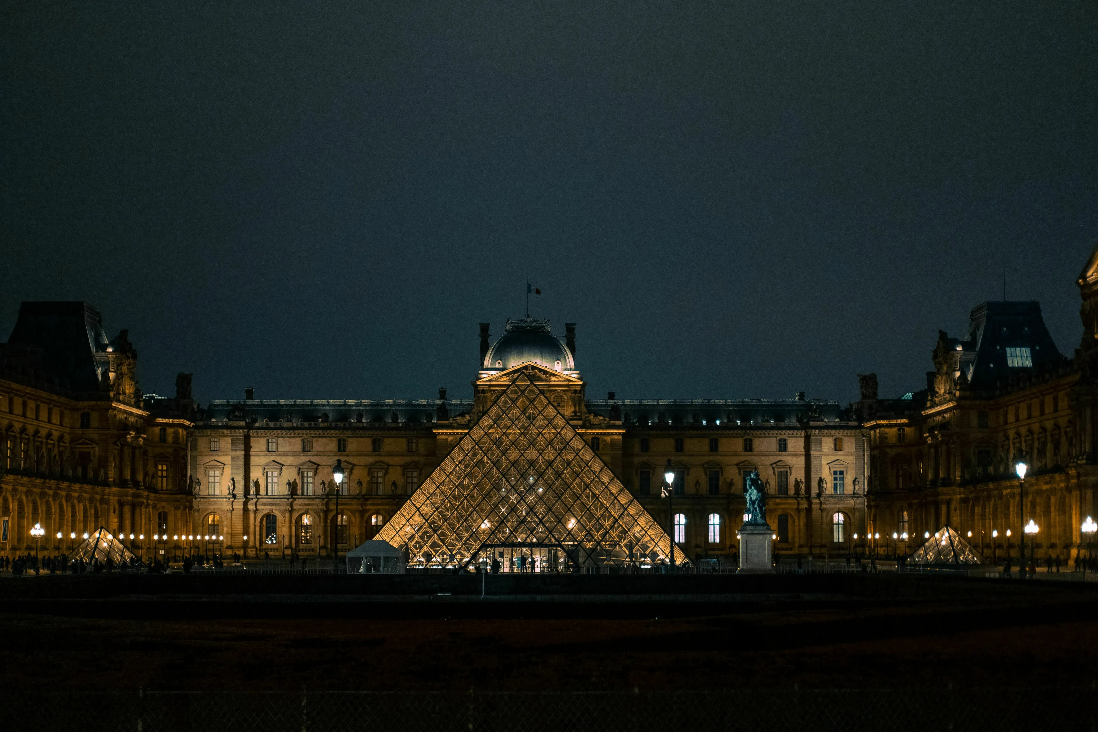 The illuminated glass pyramid and facade of the Louvre museum in Paris at night