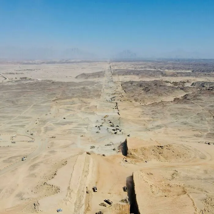 Aerial view of massive earthworks in a vast desert landscape showing major world infrastructure under construction