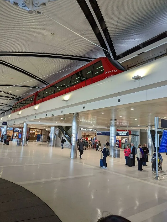 A sleek red Delta train on an elevated track inside a modern airport terminal showcasing world infrastructure