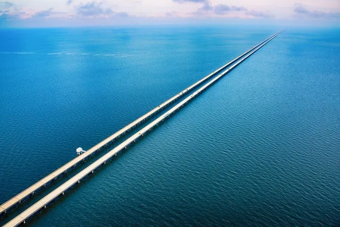 Aerial view of the Lake Pontchartrain Causeway, a long highway bridge infrastructure crossing water.
