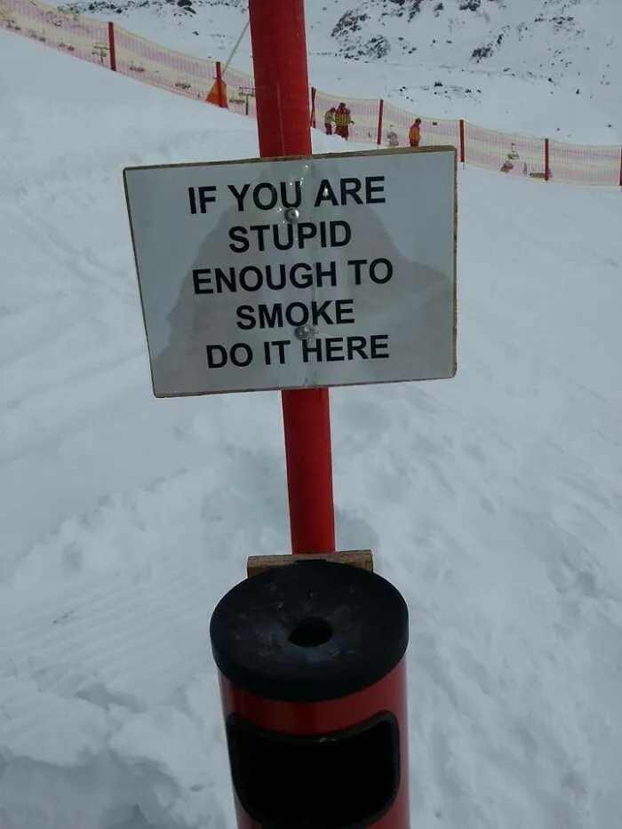 Funny smoking sign on snowy mountain saying stupid smokers should smoke here