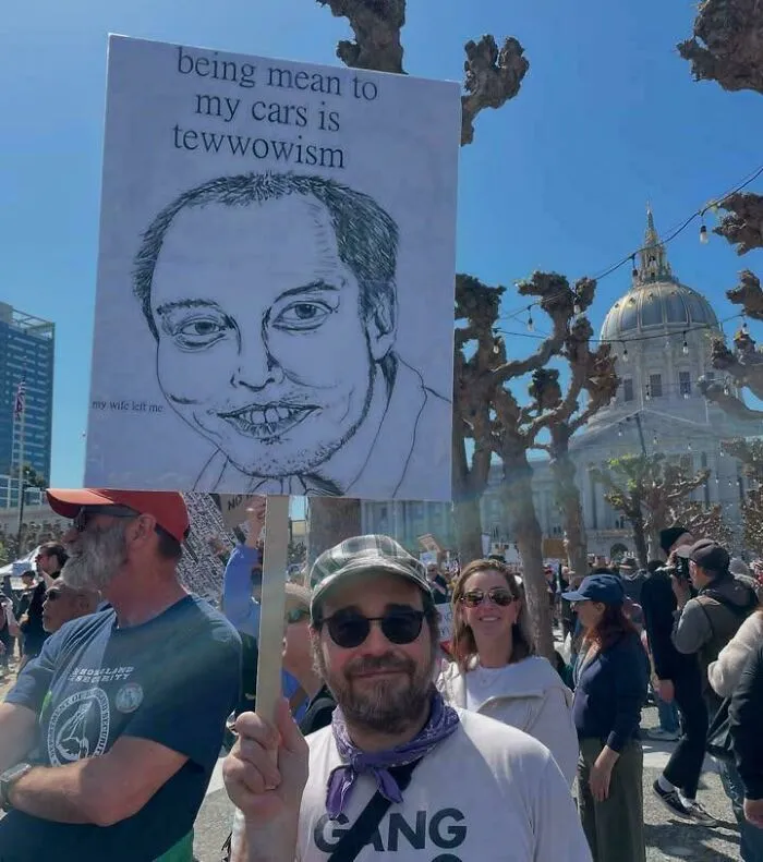 Protestor holding sign with caricature and joke about being mean to cars