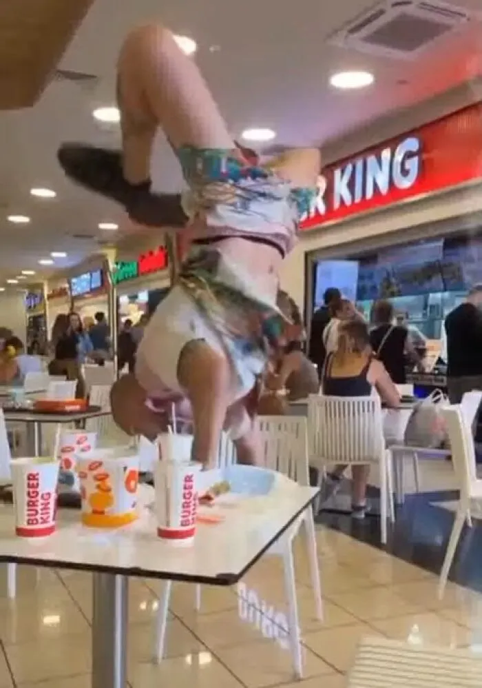 A person doing a handstand on a fast food restaurant table, exemplifying main character lives behavior.