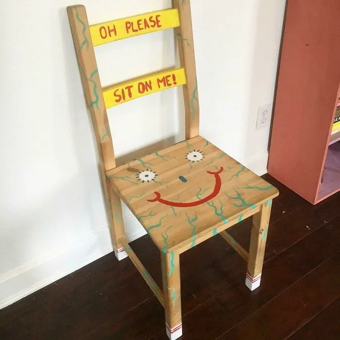A weirdly painted wooden chair with a smiling face, showing an unconventional design idea for houses