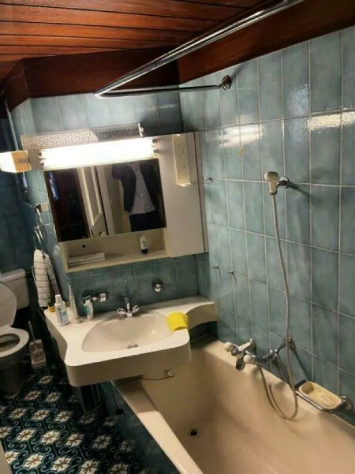 Awkwardly designed houses featuring a bathroom sink installed directly over a bathtub with blue tiling
