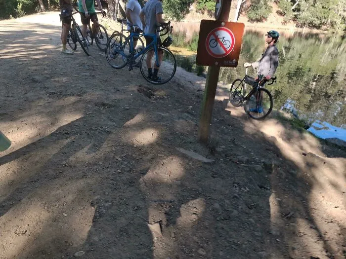 Cyclists ignoring a no bike sign, depicting main character lives behavior