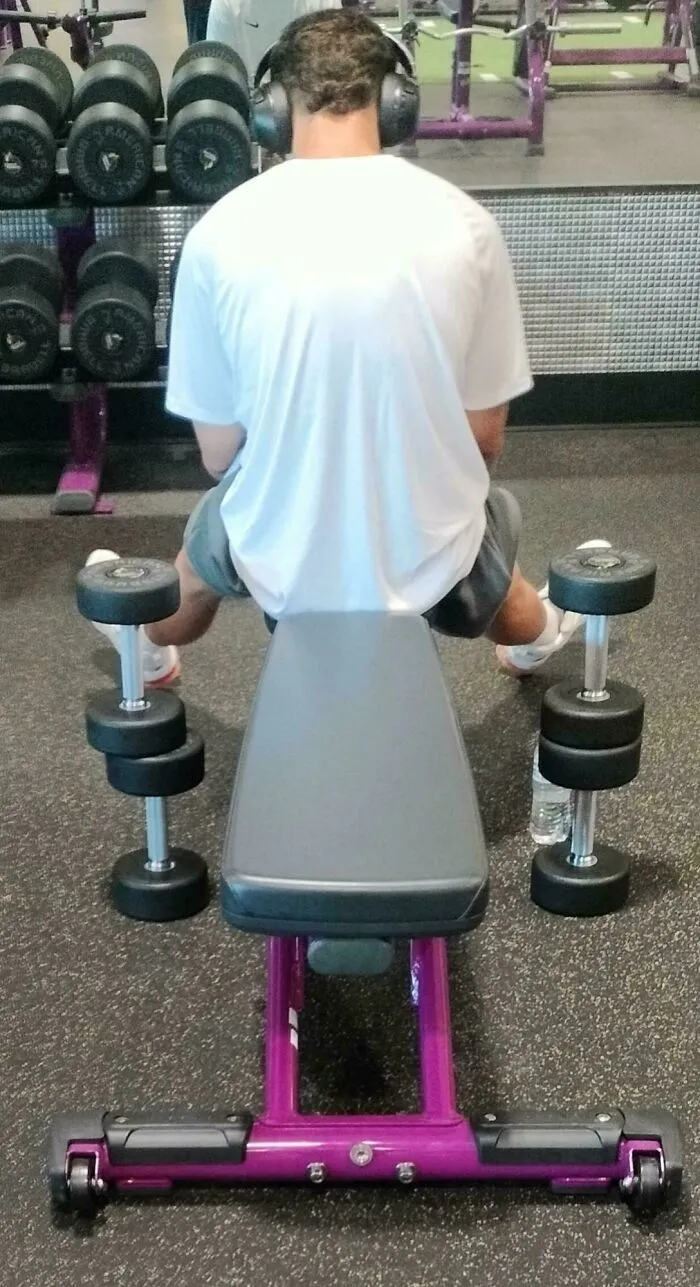 A person with a main character attitude hogging several dumbbells and a gym bench.