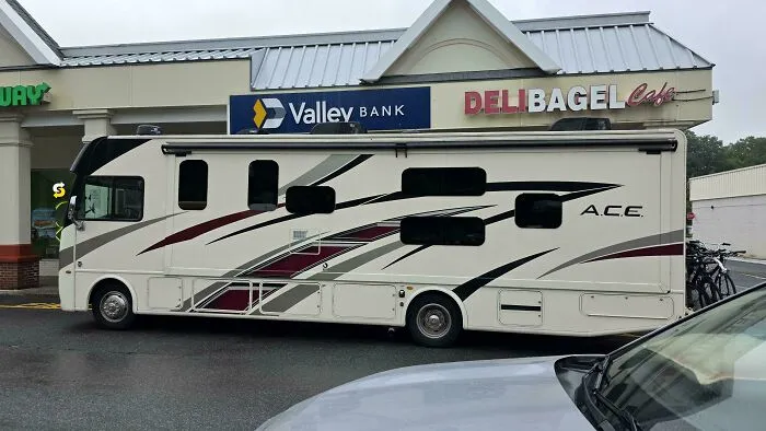 Large recreational vehicle parked horizontally across multiple spaces, showcasing main character vibes.