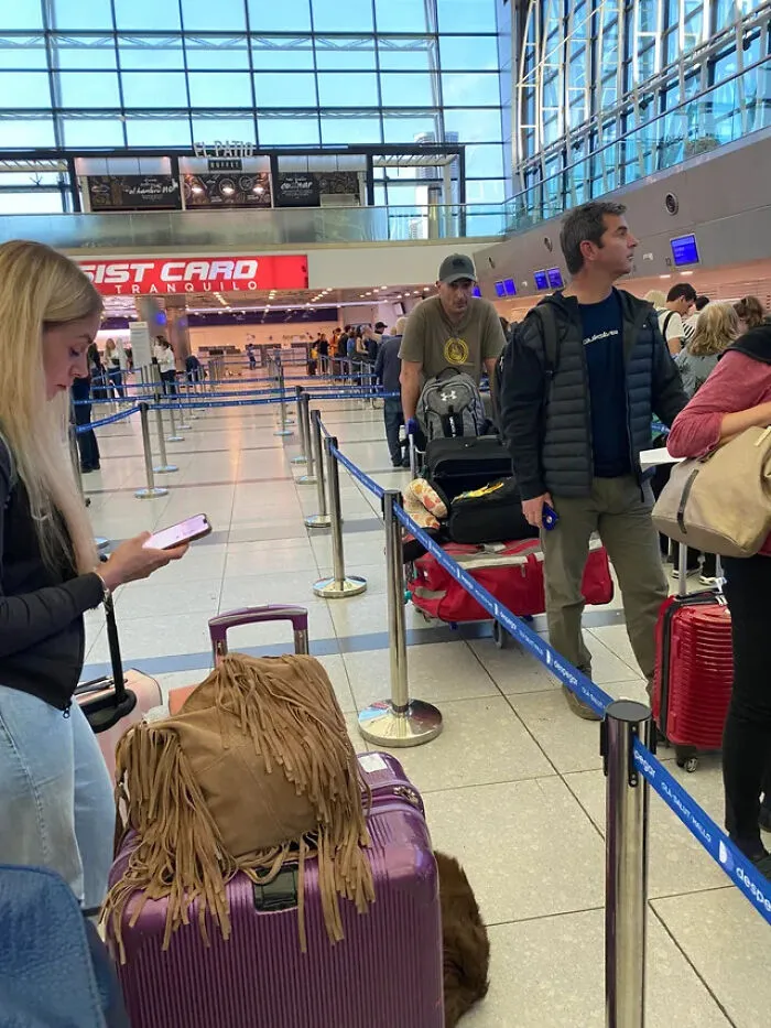 A woman on her phone blocking others in line showing main character energy
