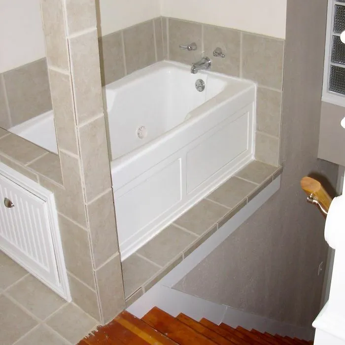 A bathtub installed dangerously close to a staircase opening in a house with poor layout