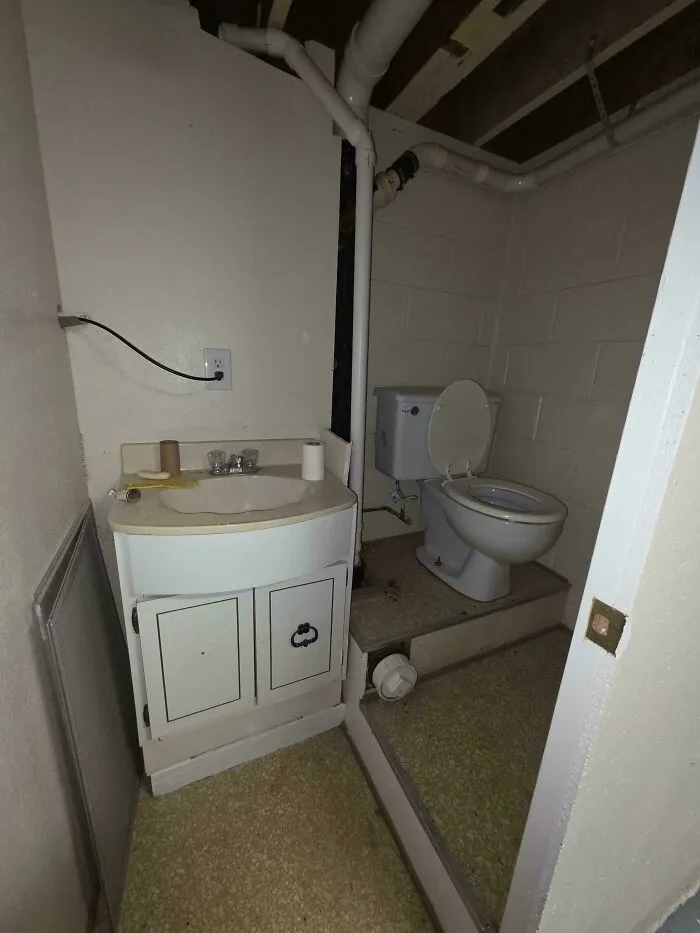 An oddly configured basement bathroom with a raised toilet, typical of unusual layouts in some houses.