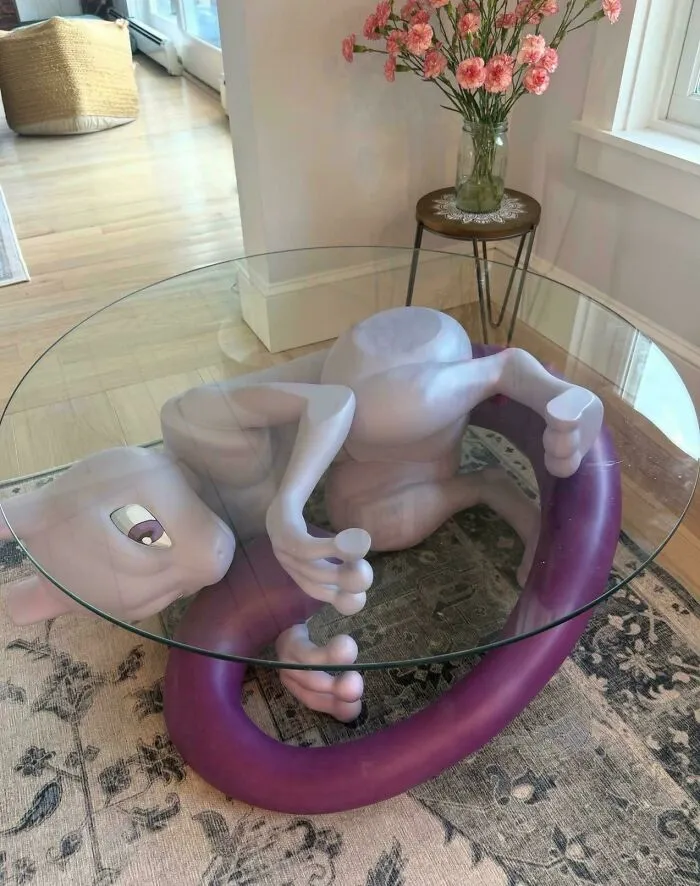 A glass coffee table supported by a Mewtwo statue in houses