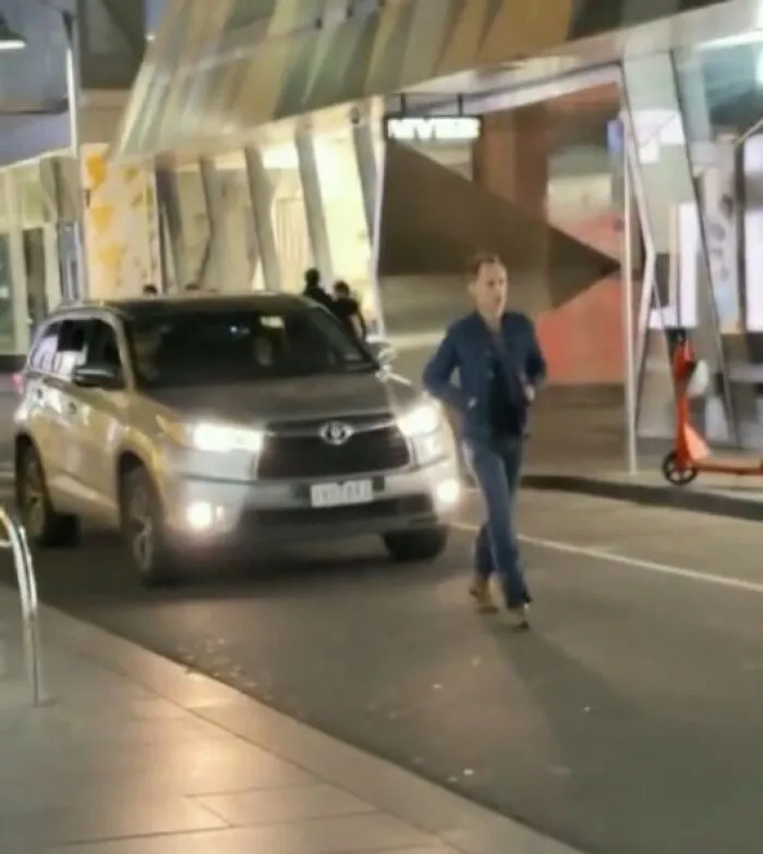 A pedestrian walks in front of a moving SUV on a city street, epitomizing main character lives.