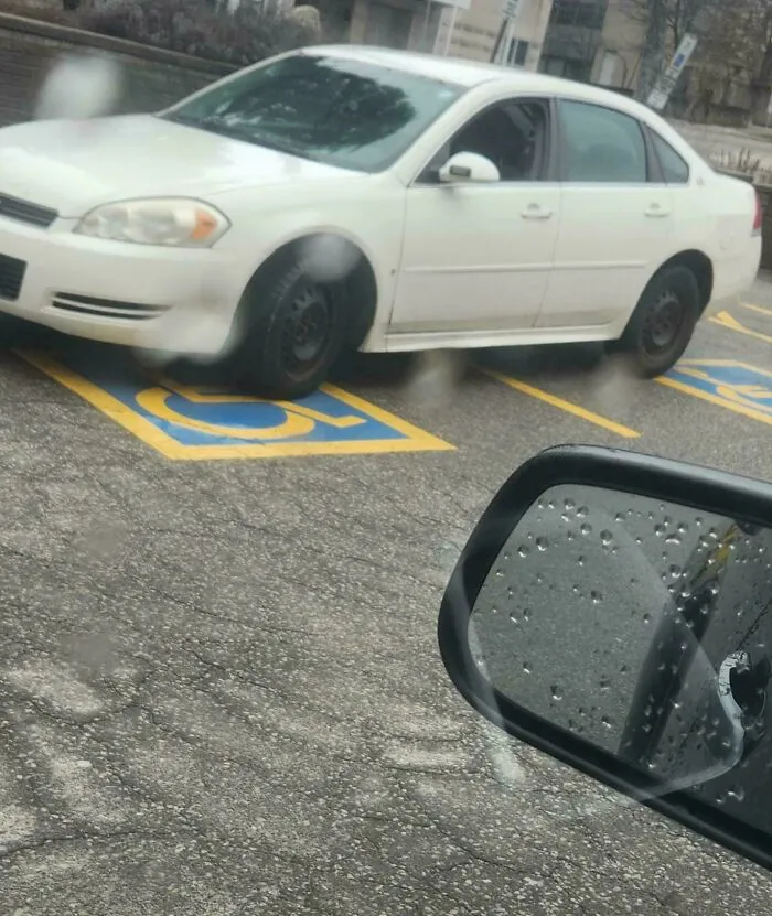 White sedan parked sideways across two handicapped parking spaces, depicting main character lives.