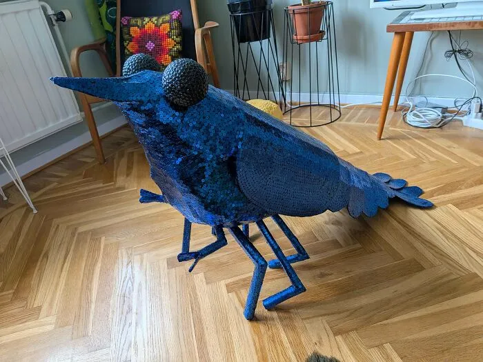A large blue sequined bug sculpture standing on a wooden floor, representing odd decorations in houses.