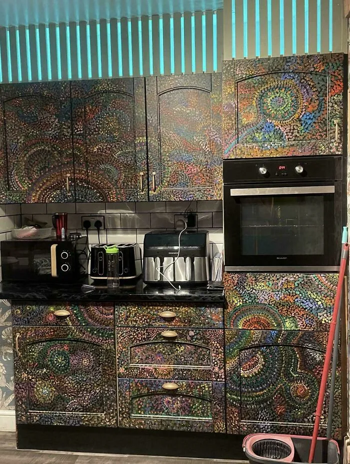A kitchen setup with cabinets fully decorated in colorful, chaotic dot art patterns, representing houses with a big vision.