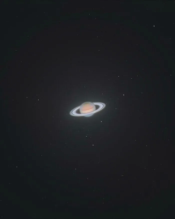 A cool photo of the planet Saturn and its visible rings glowing in the dark night sky.