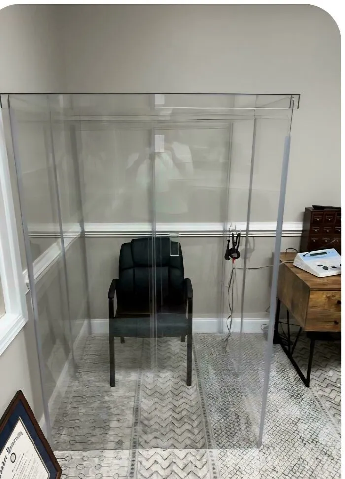 A black office chair placed inside a transparent plastic enclosure, demonstrating a weird home layout.