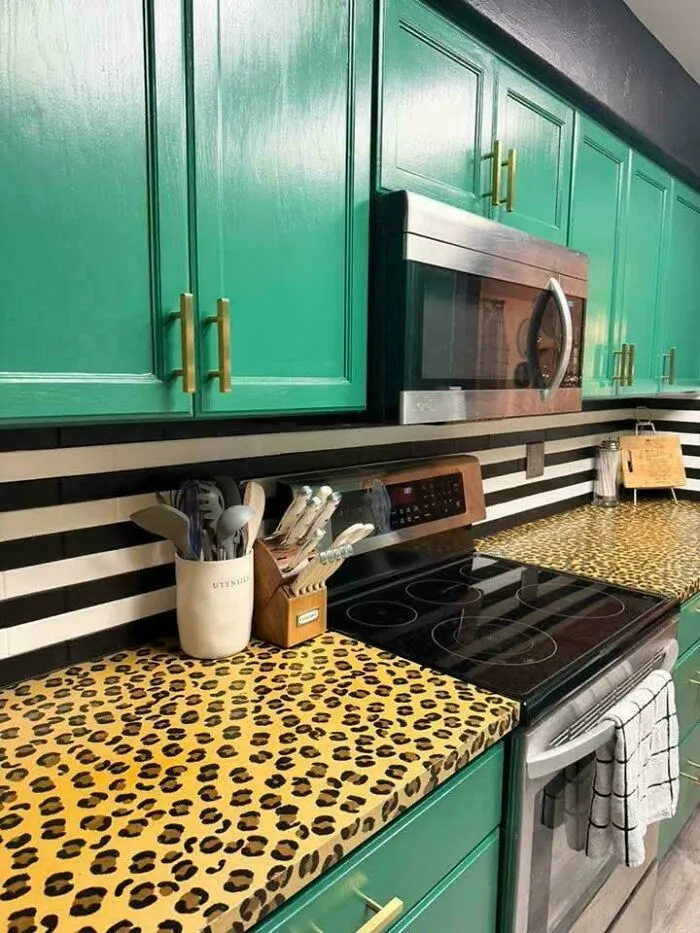Bright green kitchen cabinets paired with a striking leopard print countertop in a house with bold design.