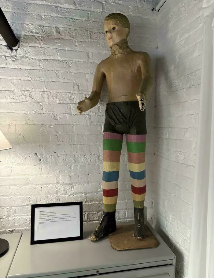 A strange antique mannequin of a boy with striped legs in a room with quirky home decor choices.