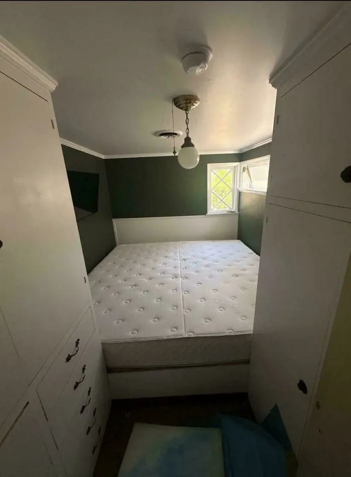A mattress squeezed tightly between two white closets in a small room, showing a poorly planned house layout.