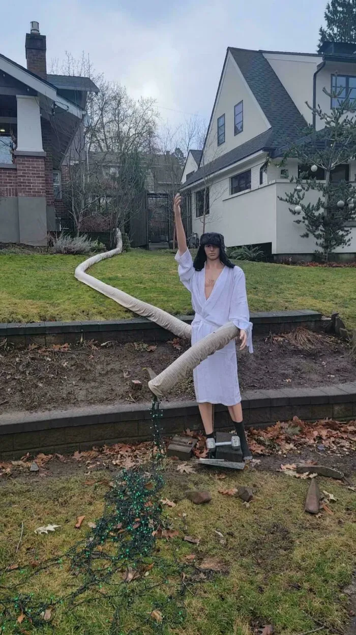 A mannequin dressed in a bathrobe standing in a front yard, representing houses with an odd design vision.