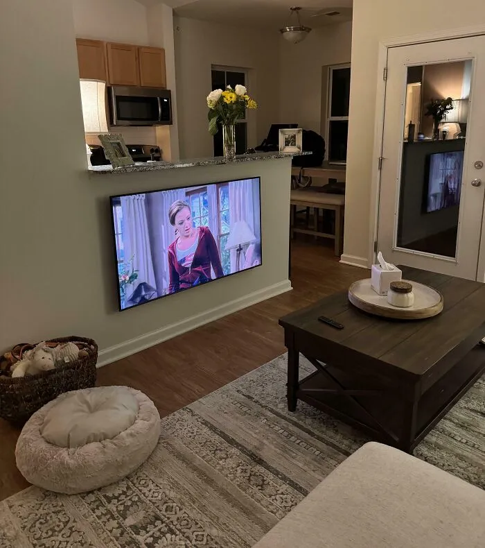 A television awkwardly mounted on a low kitchen half-wall below the countertop level.