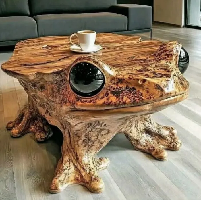 A hand-carved wooden frog coffee table featuring glossy black eyes and detailed webbed feet in a living room.