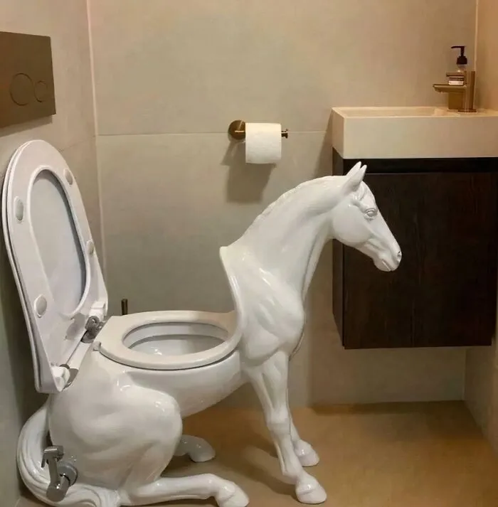 An unusual white toilet shaped like a kneeling horse, with the toilet seat on the horse's back.