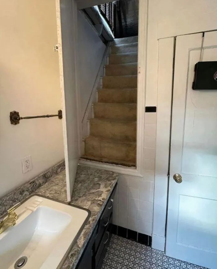 Strange houses design showing a narrow carpeted staircase starting directly above a bathroom counter