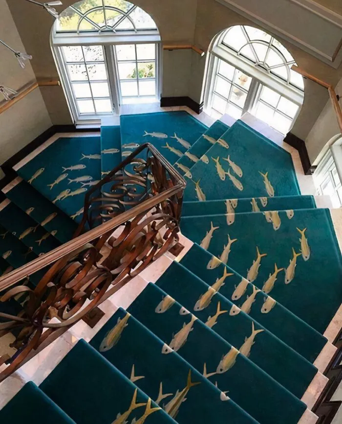 A spiral staircase with a fish-patterned blue carpet depicting questionable houses decor