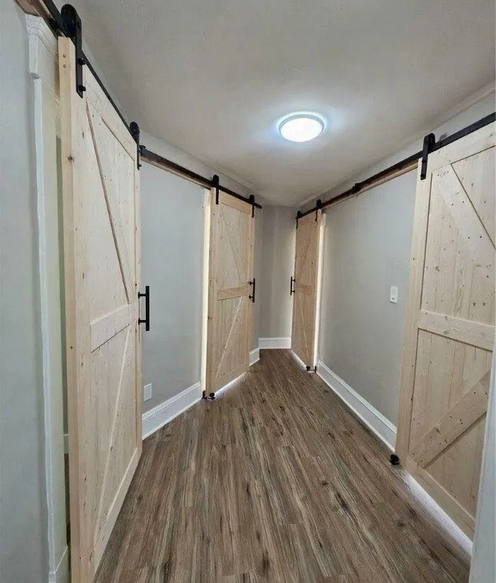 An oddly designed hallway with four wooden sliding barn doors in a house