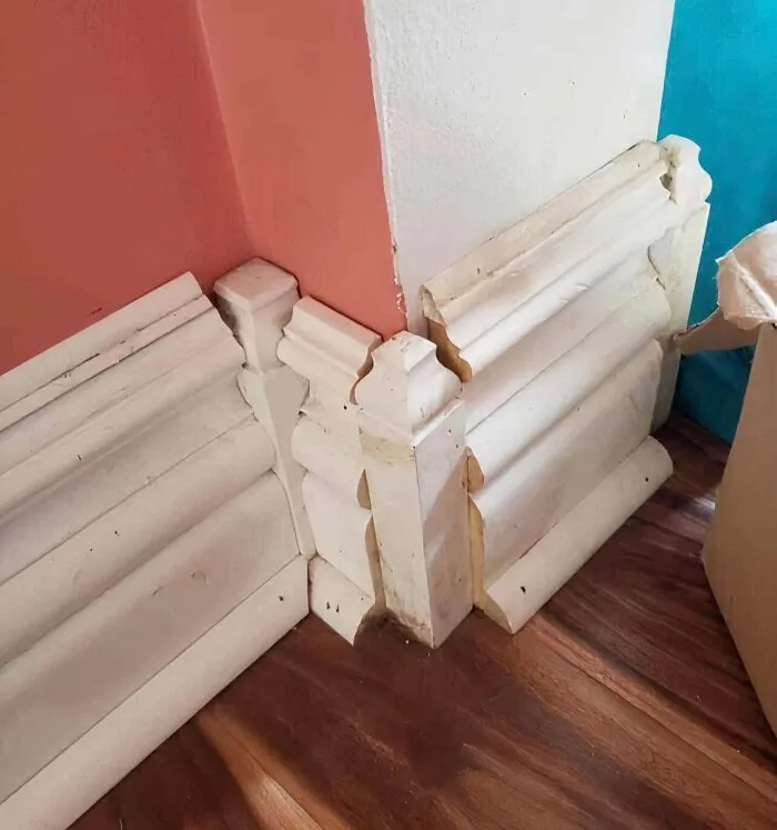 Poorly aligned and layered white baseboard trim houses construction mistake.