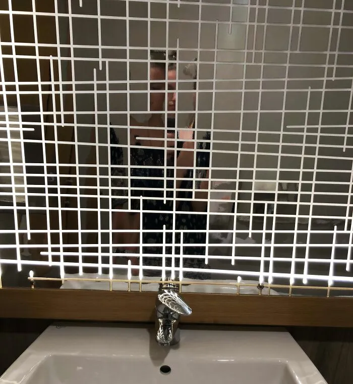 A poorly designed bathroom mirror with a chaotic white grid pattern obscuring the reflection