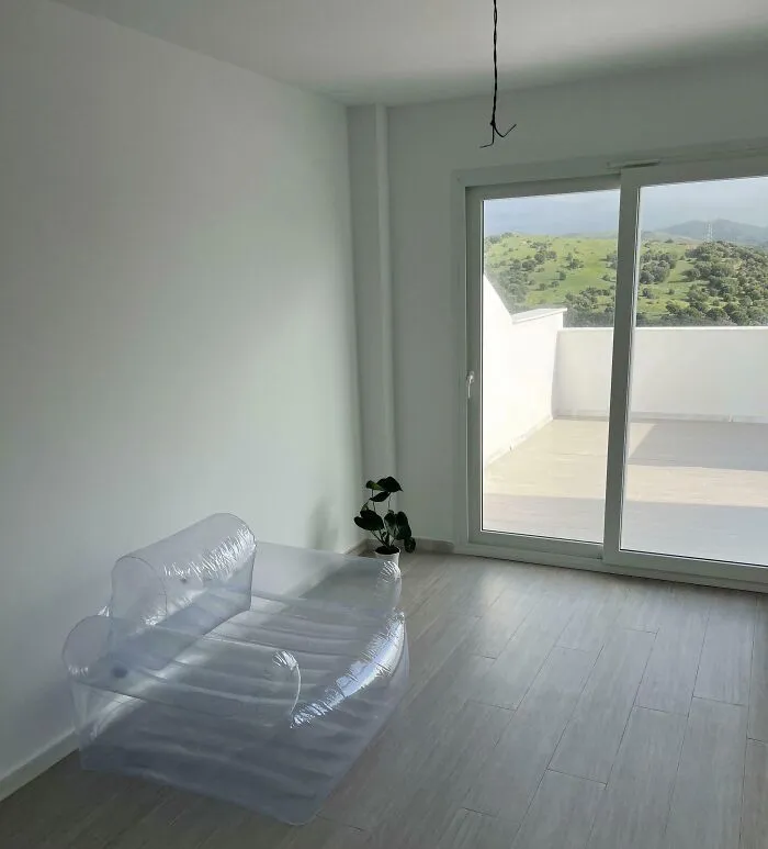 Minimalist houses living room design featuring a clear inflatable plastic sofa on a wooden floor